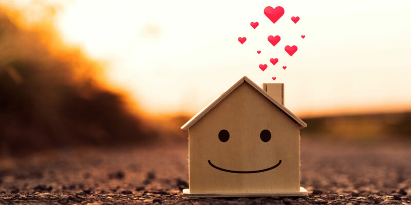 Closeup mockup house wood with face smile emotion and heart at sunset background. Minimal design. House construction and decorate concept.